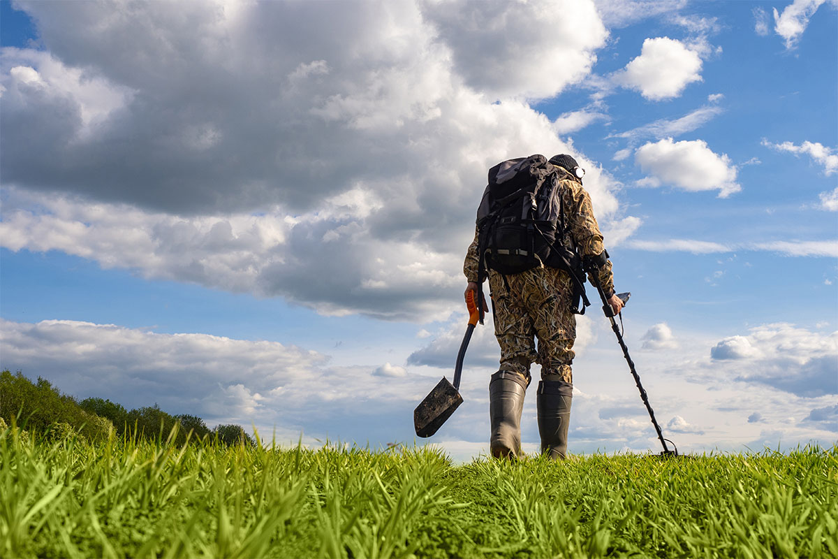 Metal detectorist walking across a field